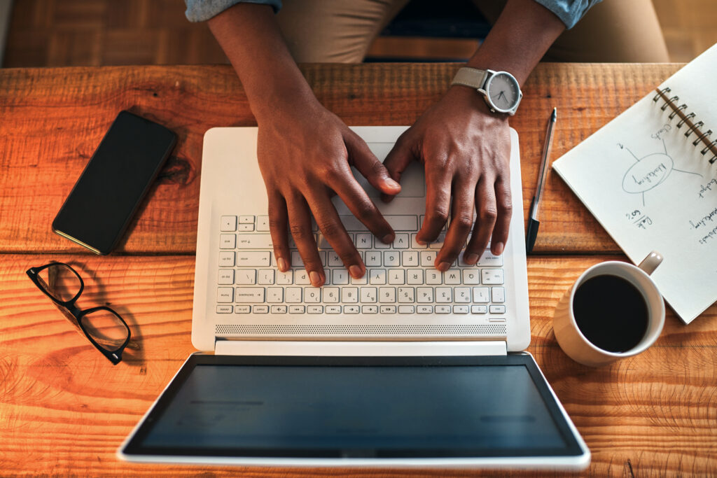 High angle shot of an unrecognizable businessman sitting alone in his home office and typing on his laptop